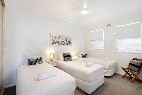 two beds and a couch in a room with windows at Blue Pacific Apartment 8 in The Entrance