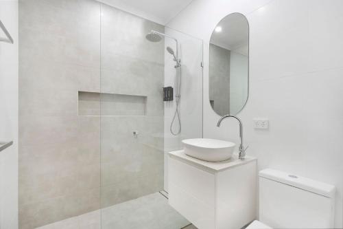 a white bathroom with a sink and a shower at Blue Pacific Apartment 8 in The Entrance