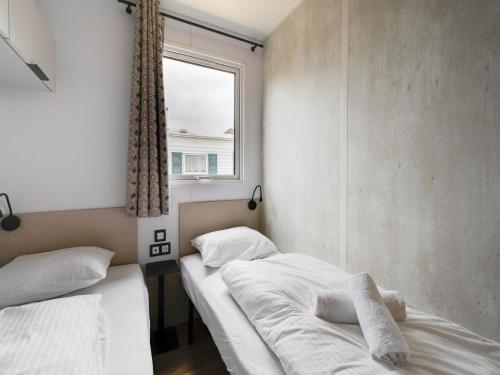 two beds in a small room with a window at Berlare Retreat for 6 with garden in Berlare