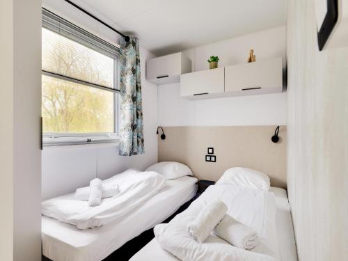 two beds in a room with a window at Cozy Caravan in Berlare for 6 people in Berlare