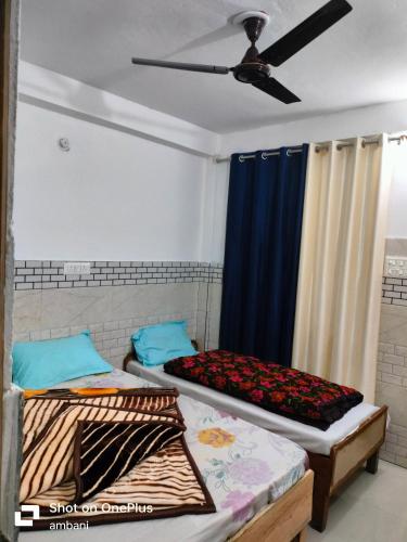 two beds in a room with a ceiling fan at Hotel suryoday kharadi in Kutnaur