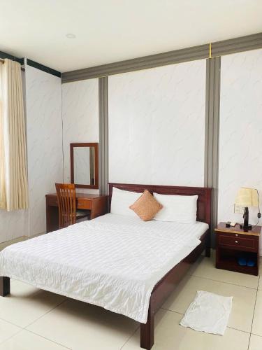 a bedroom with a bed and a table and a mirror at NGỌC MẤY - ĐẠI LỢI HOTEL in Chau Doc