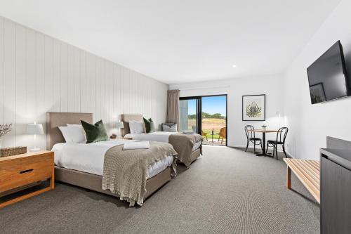 a hotel room with two beds and a flat screen tv at 13th Beach Golf Lodges in Barwon Heads