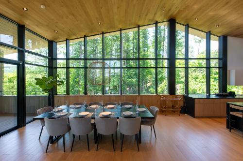 a dining room with a table and chairs and large windows at Kazahana at Hanaridge in Kutchan