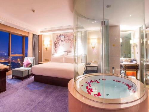 a bedroom with a bed and a tub in a room at Kasion International Hotel Yiwu in Yiwu