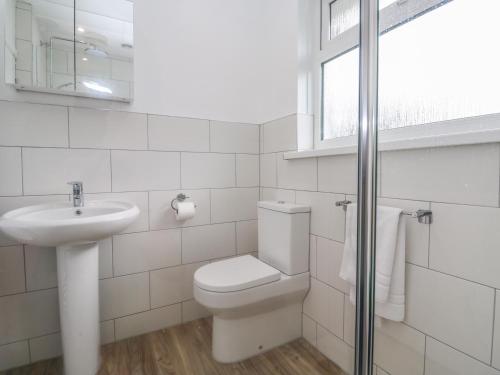 a white bathroom with a toilet and a sink at Bod A Quinte in St Ives