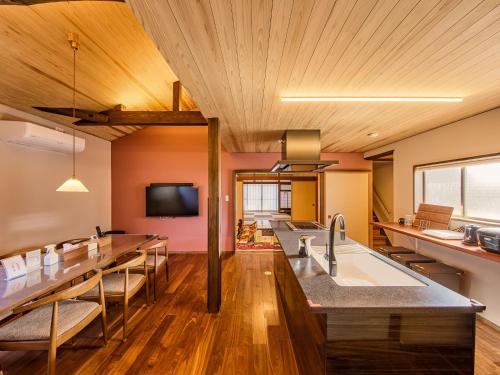 a kitchen with wooden ceilings and wooden tables and chairs at 縁や出雲 in Taisha