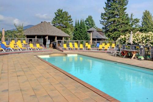 a swimming pool with chairs and a gazebo at 4-Bedroom Chalet Fraternite in Lac-Superieur Tremblant in Lac-Superieur