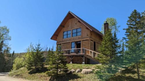 a log home on a hill with trees at 4-Bedroom Chalet Fraternite in Lac-Superieur Tremblant in Lac-Superieur