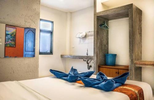 a bedroom with a bed with blue pillows on it at Six Pack Cottage in Chalong
