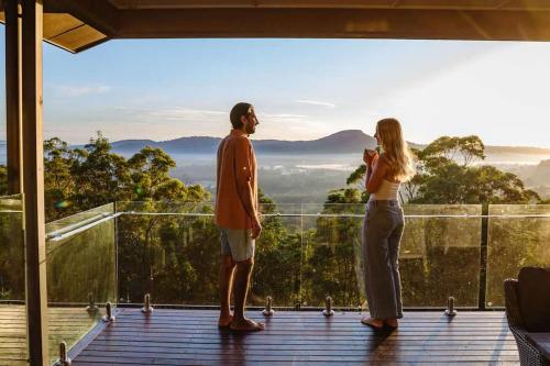 a man and a woman standing on a deck looking at the view at Wilderness House in Kulangoor