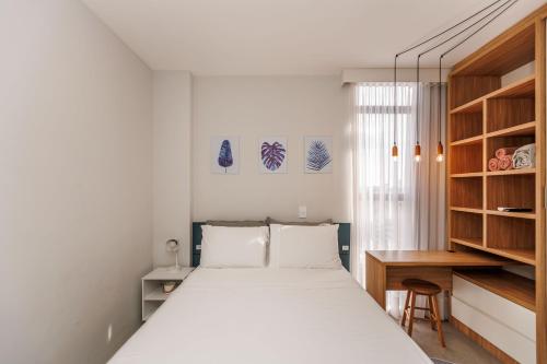 a white bedroom with a bed and a desk at Apartamento ensolarado em condomínio clube in Curitiba