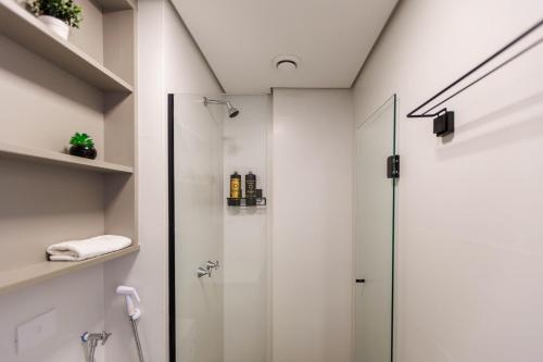 a shower with a glass door in a bathroom at Apartamento ensolarado em condomínio clube in Curitiba