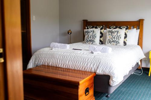 a bedroom with a bed with a wooden headboard and pillows at Aston Norwood Chalets in Upper Hutt
