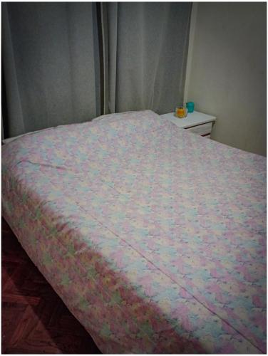 a bed with a pink comforter on top of it at Cómodo, bien ubicado y con host multilingüe in Montevideo