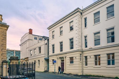 a person walking down a street in front of buildings at High Street Hideaway Cheltenham in Cheltenham