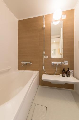 a bathroom with a tub and a sink and a mirror at Toba ryokan michishio in Toba