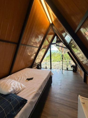 a bed in a room with a large window at Chalé refugio de Igaratá in Igaratá