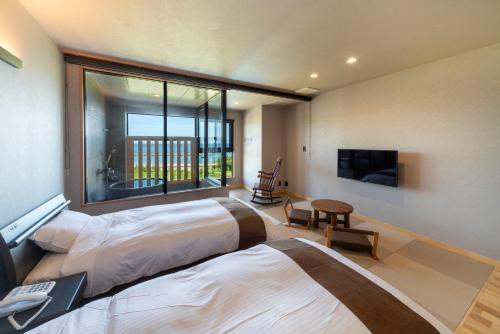 two beds in a room with a large window at Toba ryokan michishio in Toba