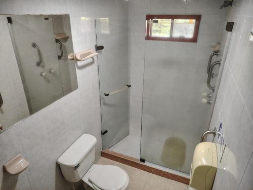 a white bathroom with a shower and a toilet at Hostal LA MIA in Armenia