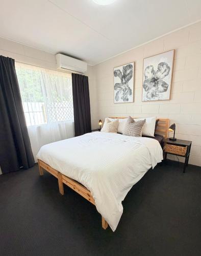 a bedroom with a large bed with white sheets and a window at 'Your Place on Davidson' Uno in Mount Isa