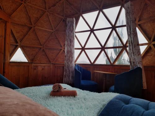 a room with a bed and two chairs and windows at Glamping Centauro in Tota