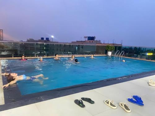 a group of people swimming in a swimming pool at Bamboo Hotel FLC Sầm Sơn in Sầm Sơn