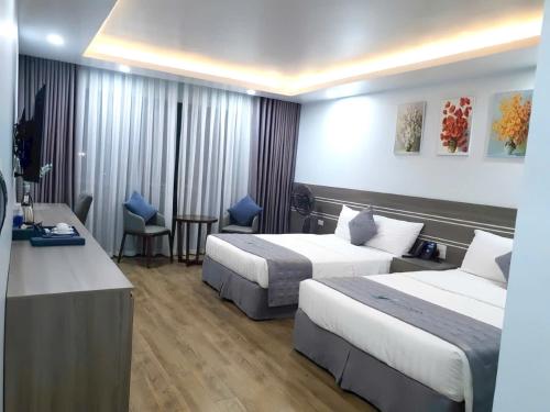 a hotel room with two beds and a desk at Bamboo Hotel FLC Sầm Sơn in Sầm Sơn