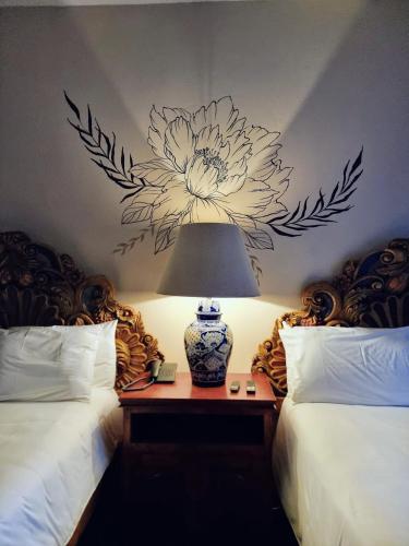 a bedroom with two beds with a flower mural on the wall at Hacienda de las Flores in San Miguel de Allende