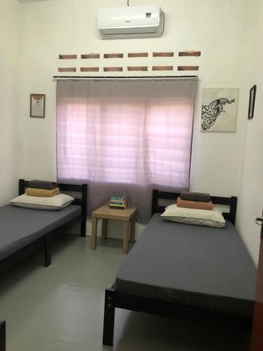 two beds sitting in a room with a window at Surf house langkawi in Pulau Tepur