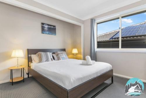 a bedroom with a bed and a large window at 3B house Central Coast parking in Blue Haven