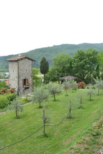 an old stone building in a field with trees at Torre del Drago in Borgo alla Collina
