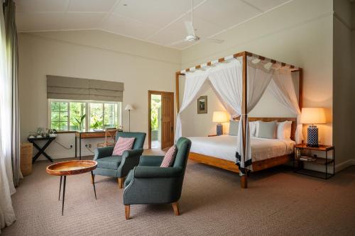 a bedroom with a canopy bed and two chairs at Nine Skies By Teardrop Hotels in Ella