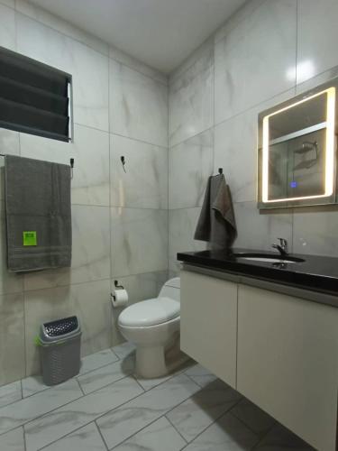 a bathroom with a toilet and a sink and a mirror at Hospedaje Smart Wasi Sucre in Sucre