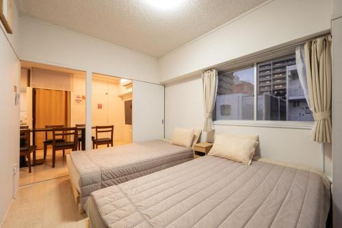 a bedroom with two beds and a table and a window at GoodStay505 in Kurume