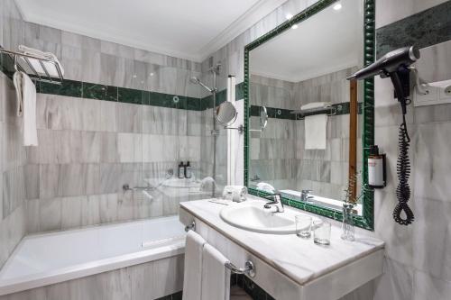 a bathroom with a sink and a tub and a mirror at SOL by Meliá Málaga Guadalmar in Málaga