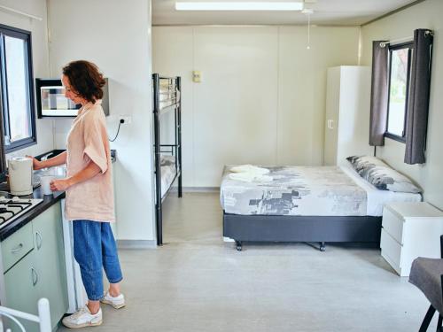 a woman standing in a room with a bed at Collie Tourist Park in Collie