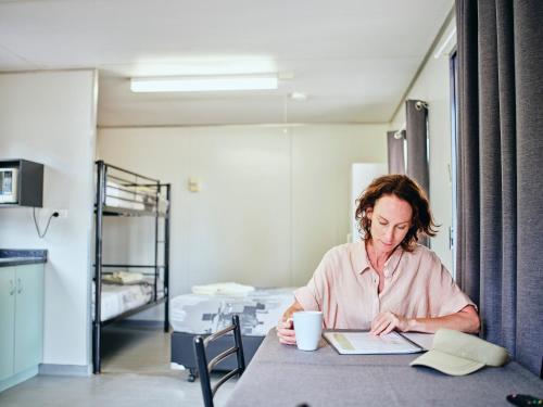 a woman sitting at a table looking at a book at Collie Tourist Park in Collie