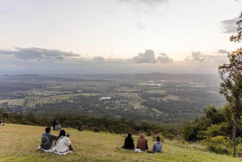 a group of people sitting on top of a hill at Cedar Creek Falls by Tiny Away in Mount Tamborine