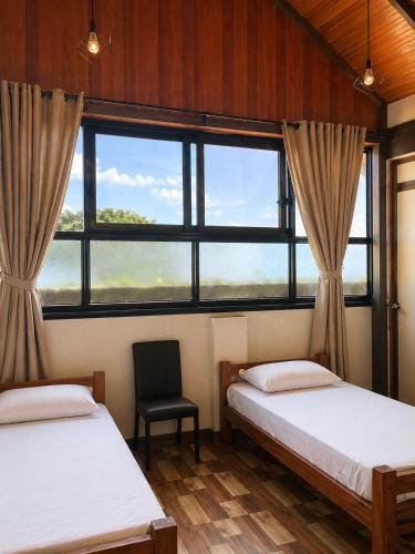two beds in a room with a large window at Coconad Resort in Alleppey