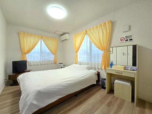 a bedroom with a bed and a desk and a television at 鶴城丸（KAKUJYOMARU） in Karatsu