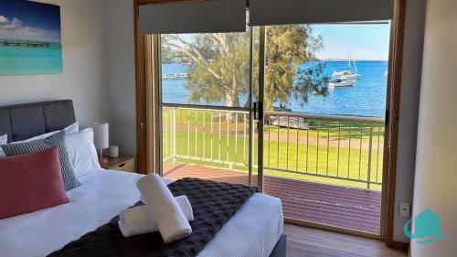 a bedroom with a bed and a view of the water at Wangi Waterfront Weekender in Wangi Wangi