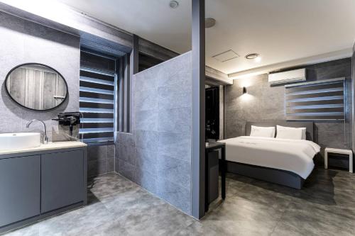 a bedroom with a bed and a sink and a mirror at Pandora Hotel in Hwaseong