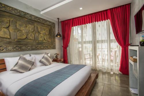 a bedroom with a large bed with red curtains at Cambana Residence in Siem Reap