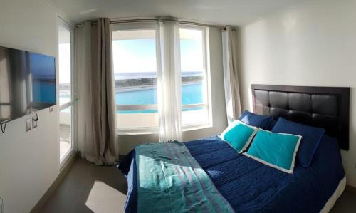 Un dormitorio con una cama con almohadas azules y una ventana en Laguna del Mar Apartamento 208, en La Serena