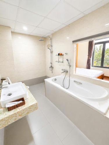 a white bathroom with a tub and a sink at An Velora Boutique Hotel in Lai Nghê (2)