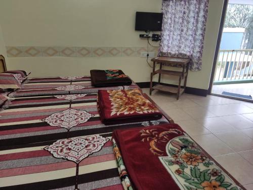 three beds are lined up in a room at Silver holidays in Yercaud