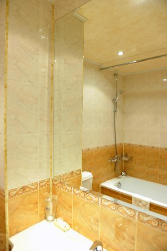 a bathroom with a tub and a sink and a mirror at Семеен Хотел Сокол in Sandanski