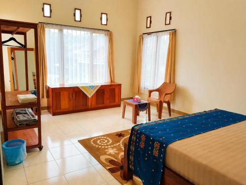 a bedroom with a bed and a chair and windows at Homestay Possere in Sadang