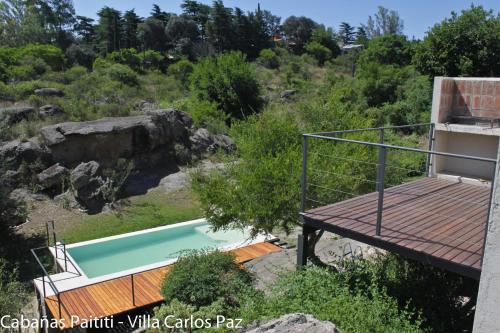 a house with a swimming pool and a wooden deck at Cabañas Paititi in Villa Carlos Paz